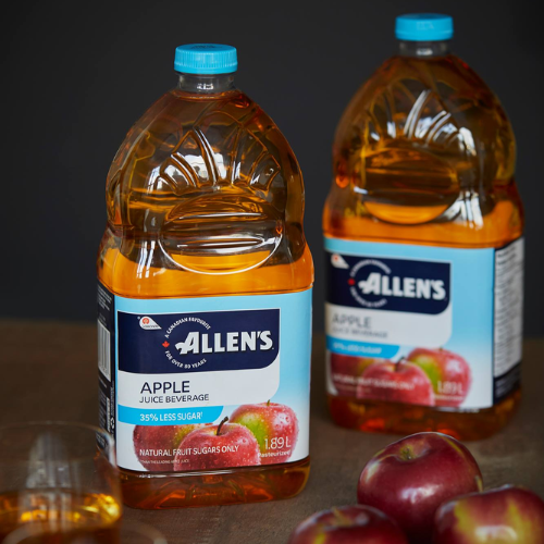 Two bottles of Allen's Apple Juice Beverage with apples on a dark background
