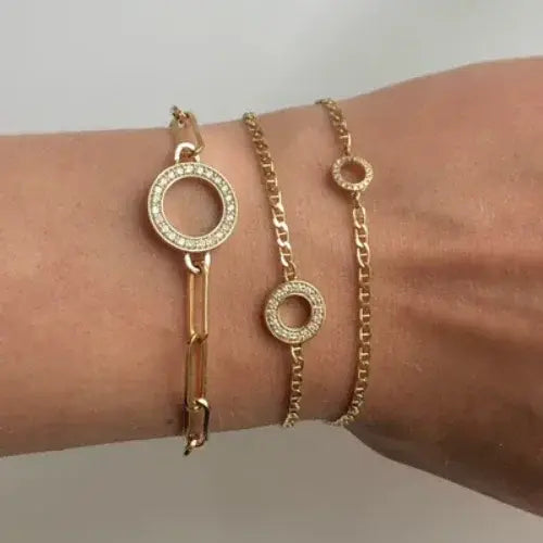 Gold bracelets on a wrist against a neutral background