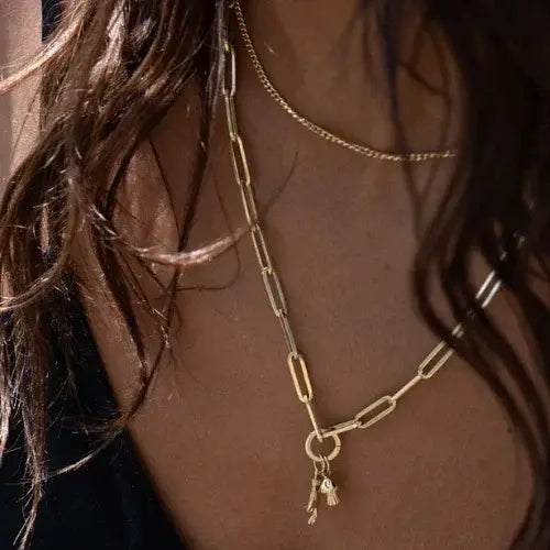 Gold chain necklace with a small pendant on a person's neck
