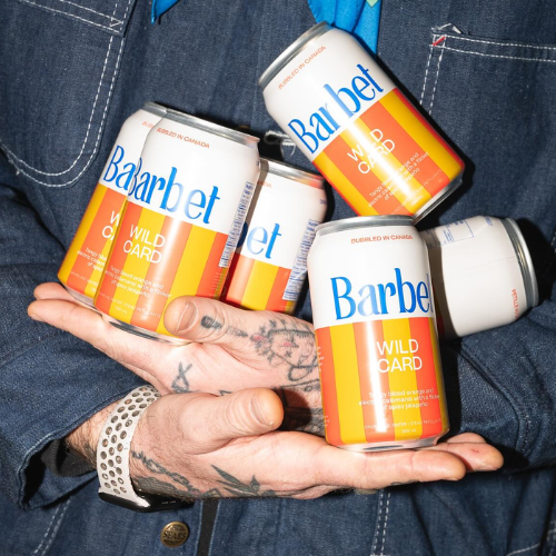 Person holding cans of Barbet wild card water beverages in their hands
