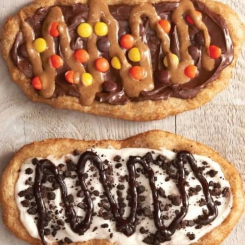 Two beavertails with different toppings on a wooden surface