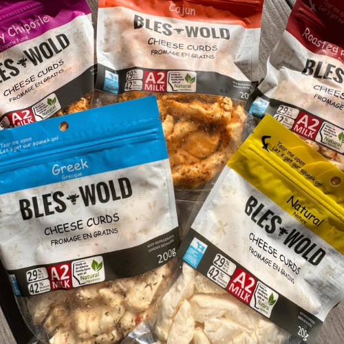Various packages of Bles Wold cheese curds on a wooden surface