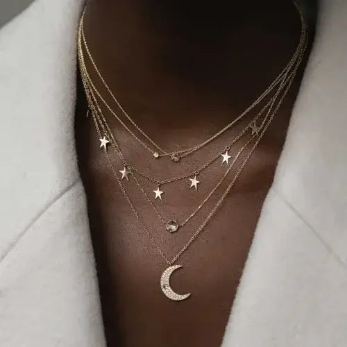 Necklace with star and moon pendants on a person wearing a light gray outfit.