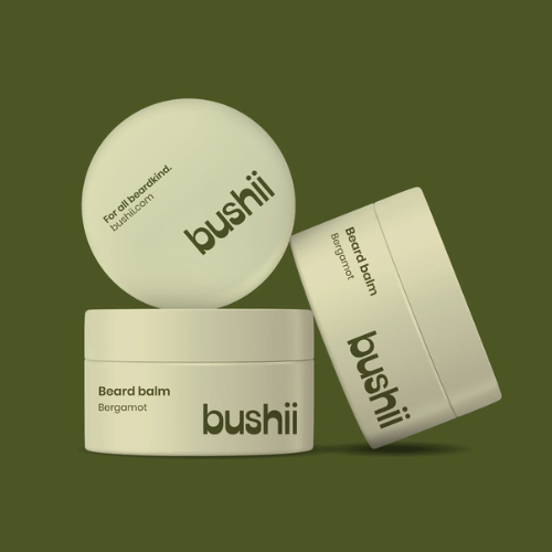 Three containers of bushii beard balm on a green background