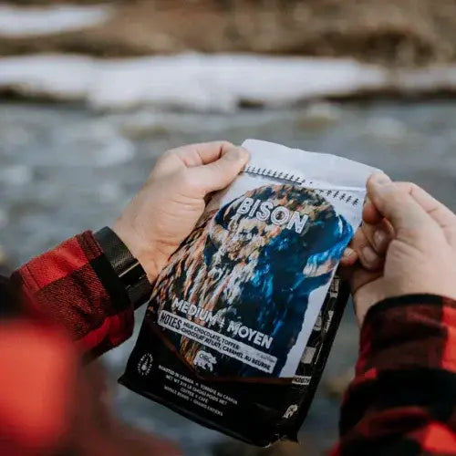Person holding a Bison brand food package by a river