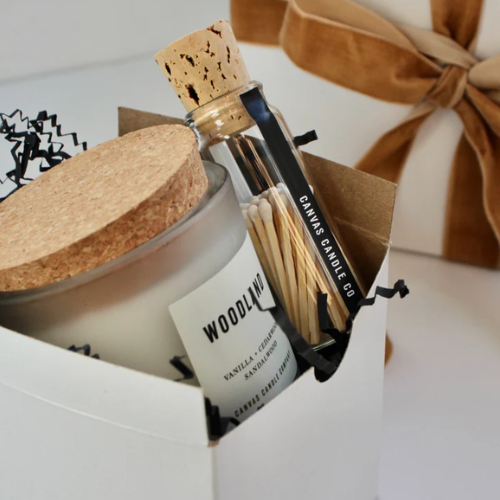 Candle with cork lid and matches in a box, branded 'Woodland Candle Co'.