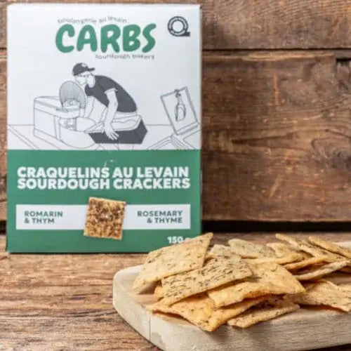 Box of CARBS sourdough crackers with crackers on a wooden board