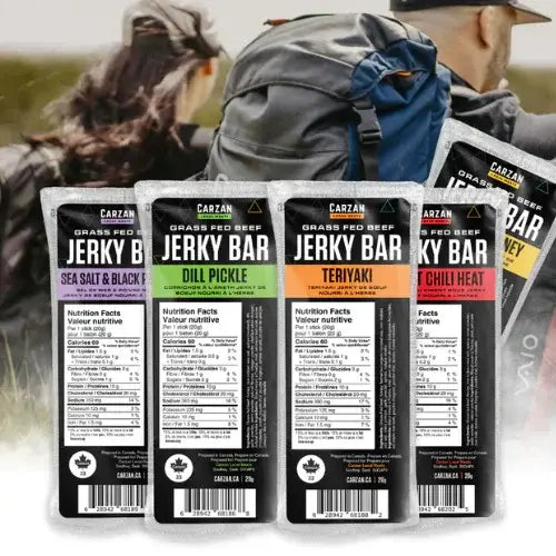Four Carzan Jerky Bar packages with different flavors displayed in front of a blurred background of people outdoors.