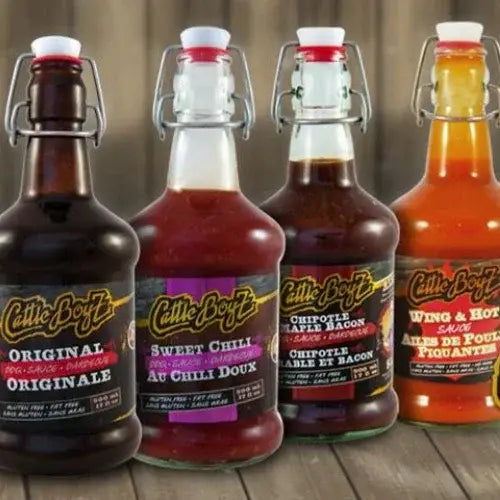 Four bottles of CattleBoyz hot sauce on a wooden surface with a rustic background.