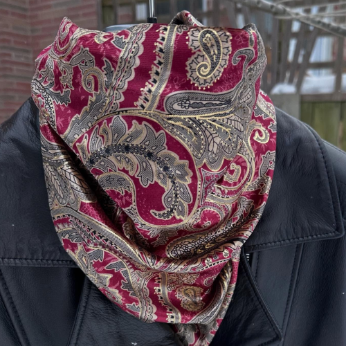 Person wearing a red paisley patterned scarf on a black jacket.