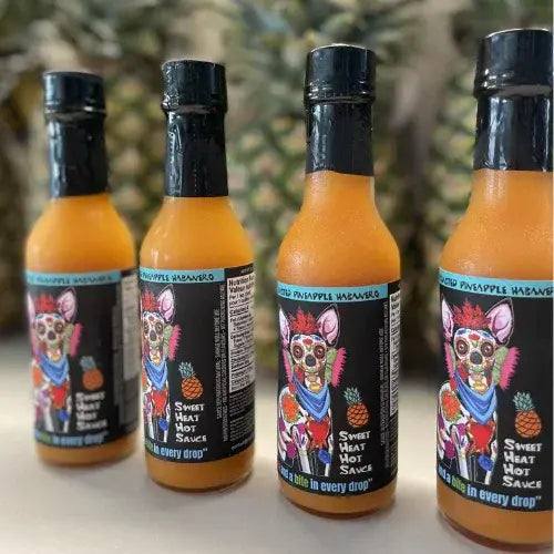 Four bottles of Sweet Heat Hot Sauce with coloUrful labels featuring a dog design on a blurred pineapple background.