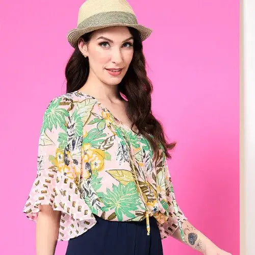 Woman wearing a floral blouse and straw hat against a pink background