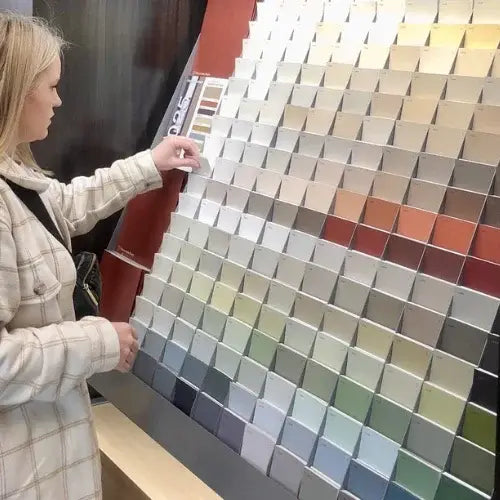 Person selecting paint colour swatches from a large display board