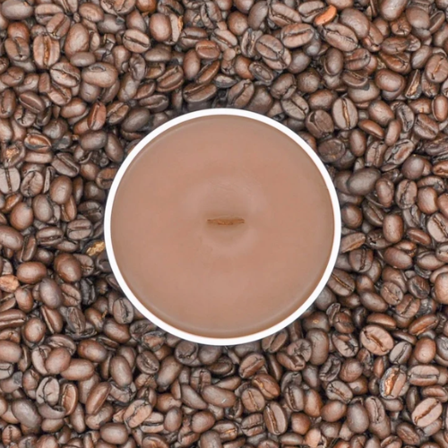A round brown candle with a white rim sits centered on a dense background of roasted coffee beans.