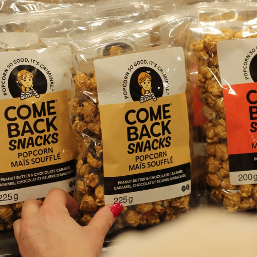 Hand holding a package of Comeback Snacks popcorn with visible branding.