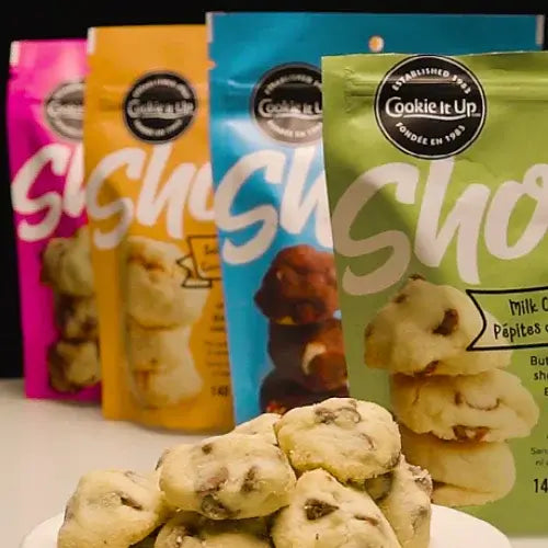 Assorted packages of 'Cookie It Up' cookies with a close-up of cookies in the foreground.