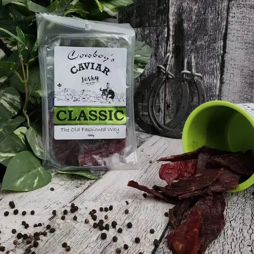 Packaged beef jerky with a label reading 'Cowboy's Caviar Jerky' on a rustic wooden surface.