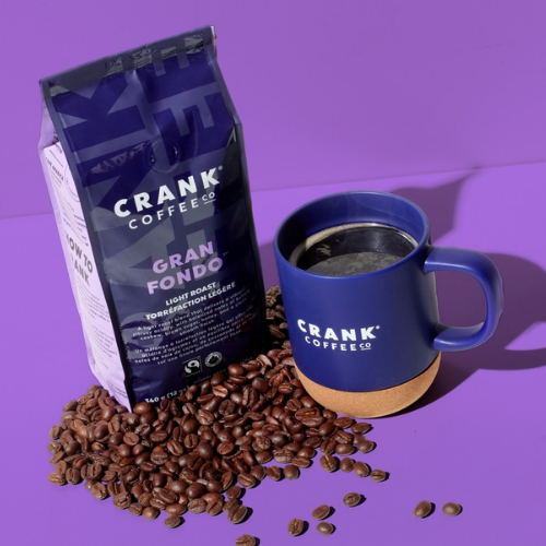 Crank Coffee package, blue mug with coffee, and coffee beans on a purple background