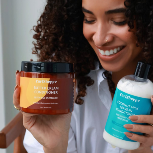 Woman holding CurlShoppe Butter Cream Conditioner and Coconut Milk Leave-In Conditioner