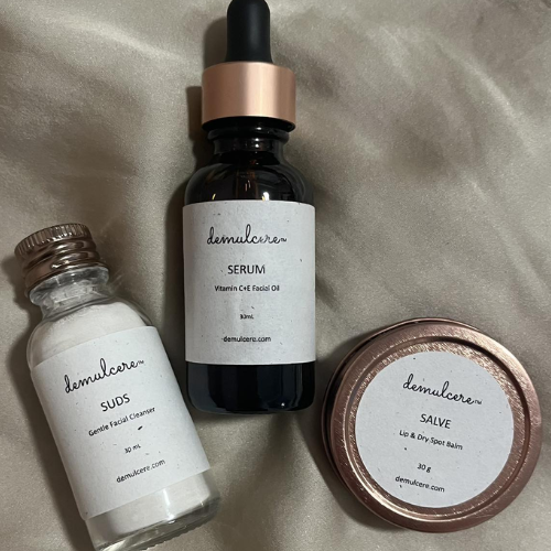 Three skincare products from demulcere on a beige fabric background