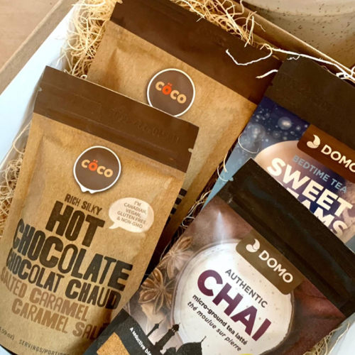 A gift box arrangement of coffee and tea products, including three bags of cácó hot chocolate, a bag of Domo Sweet Dreams Chaé, and a box of Domo Bedtime Tea.