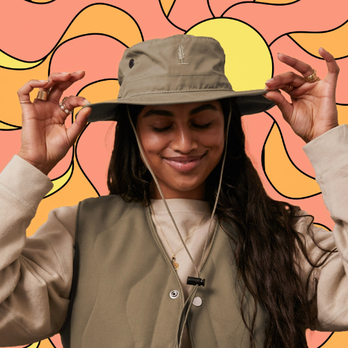 Person wearing a beige hat and jacket against a colourful abstract background