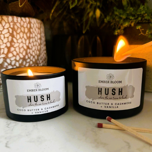 Two Ember Bloom candles labelled 'Hush' on a marble surface with a blurred background.