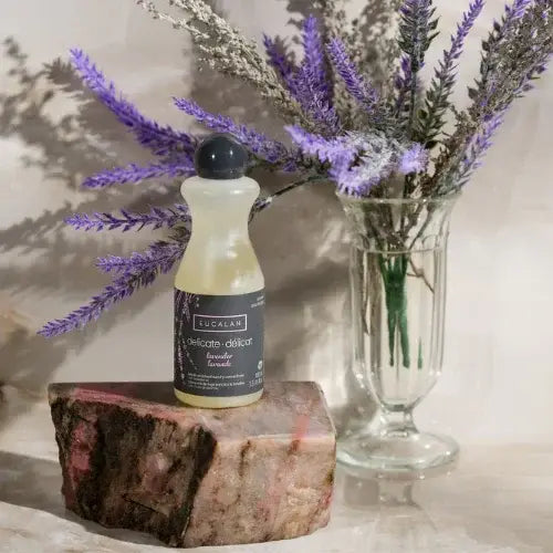 Bottle of Eucalan on a stone surface with lavender flowers in the background