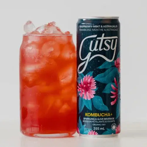 Gutsy kombucha can with a glass of red drink on a white background