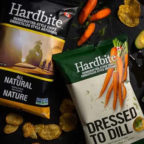 Two Hardbite chip packages, one labelled 'All Natural' and the other 'Dressed to Dill', with chips and carrots on a dark surface.