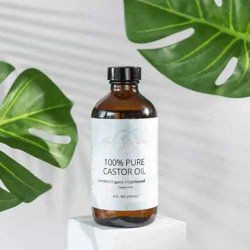 Bottle of 100% Pure Castor Oil with a label on a white background with green leaves.