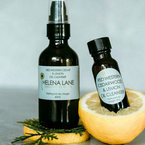 Two bottles of Helena Lane Red Western Cedarwood & Lemon Oil Cleanser with a lemon on a gray background.