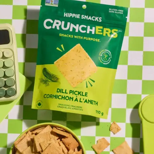 Packaging of Hippie Snacks Crunchers Dill Pickle flavor crackers on a green checkered background.