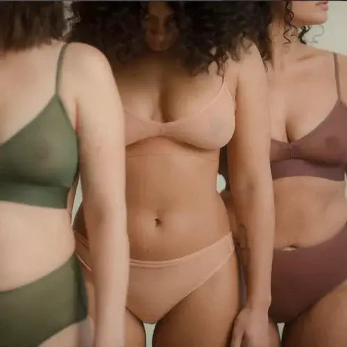 Three women wearing different colored lingerie against a neutral background