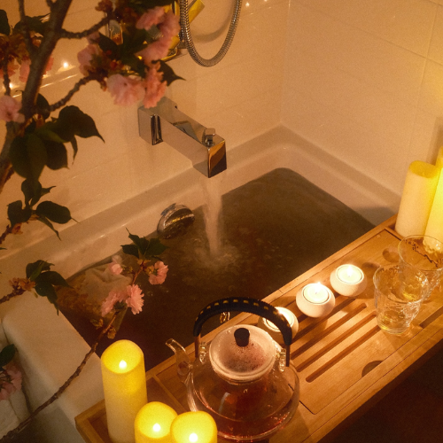 Bathroom setting with a bathtub, candles, and a teapot.