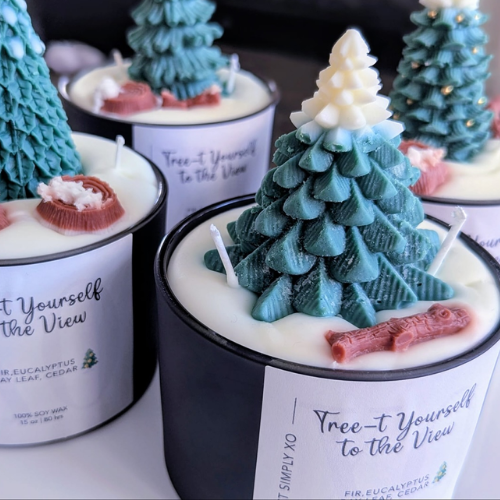 Candle with Christmas tree design and decorative elements on a white surface