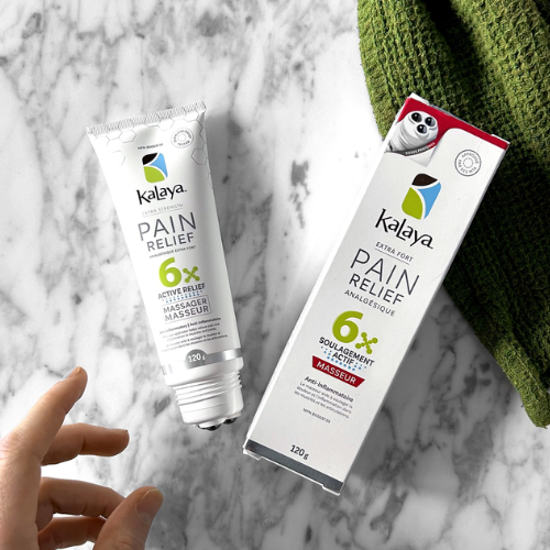 Kalaya Pain Relief cream tube and packaging on a marble surface with a green glove.