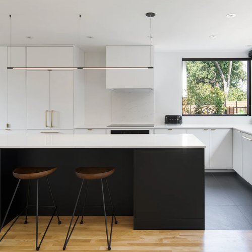 Modern kitchen with white cabinets, black island, and wooden stools.