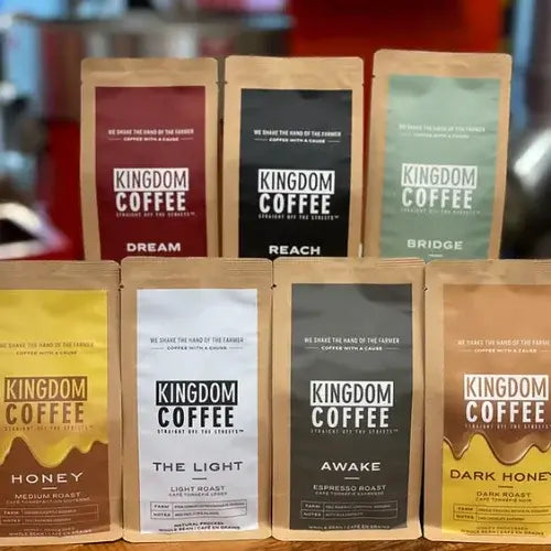 Collection of Kingdom Coffee packages on a wooden surface with a blurred background.