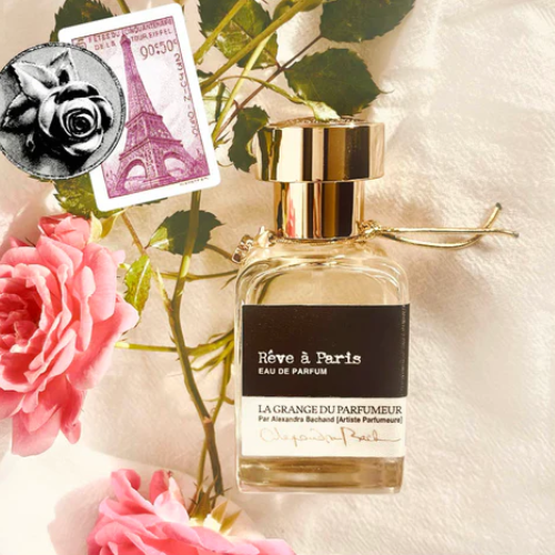 Perfume bottle with 'Rève à Paris' label surrounded by flowers and a rose stamp.