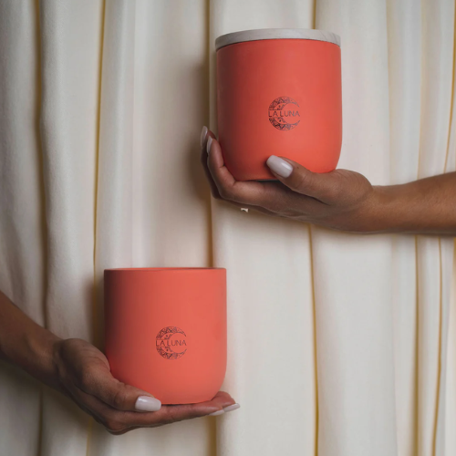 Two hands holding orange candles on a light background