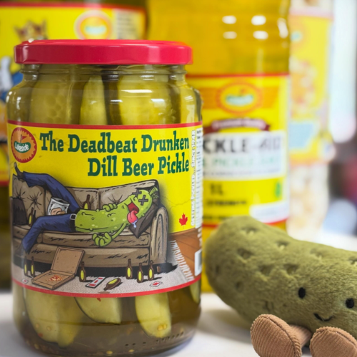 Jar of 'The Deadbeat Drunken Dill Beer Pickle' with a humorous label and a plush pickle toy.