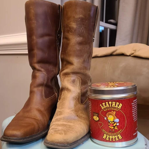 Pair of worn brown leather boots next to a can of leather conditioner on a light blue surface.