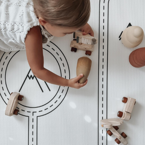 Child playing with wooden toys on a white mat with black line design