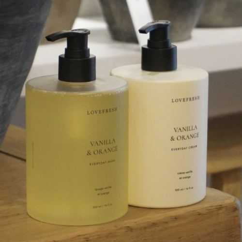 Two bottles of Lovefresh Vanilla & Orange products on a wooden surface.