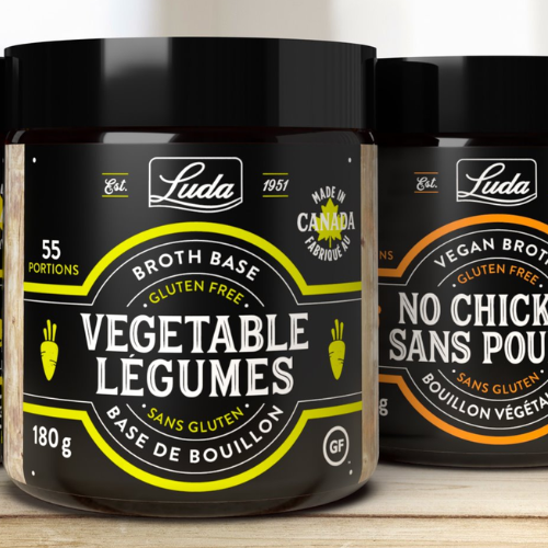 Two containers of Luda broth base on a wooden surface with a white background