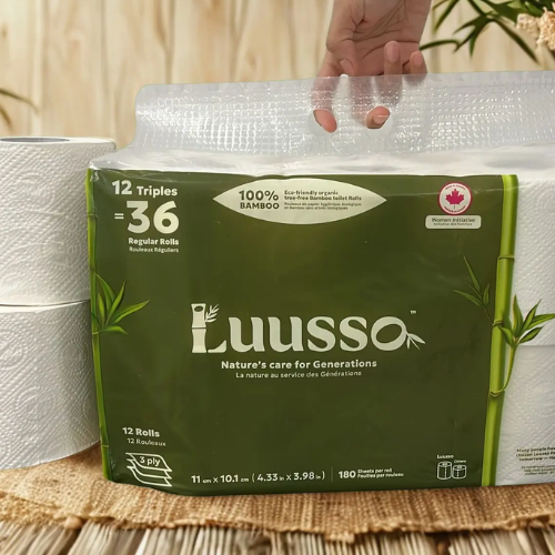 Luusso paper towel package with a hand lifting the lid on a wooden surface