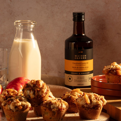 Muffins with a bottle of olive oil and a glass of milk on a wooden surface.