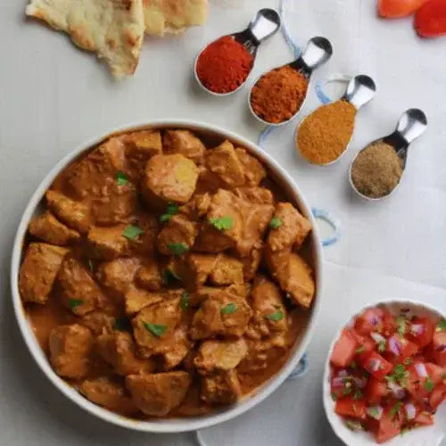 Bowl of curry with spices and bread on a table