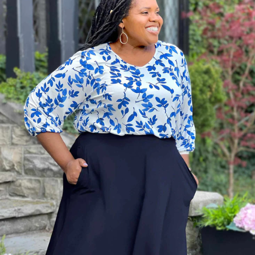 Woman wearing a blue and white floral top and black pants outdoors.